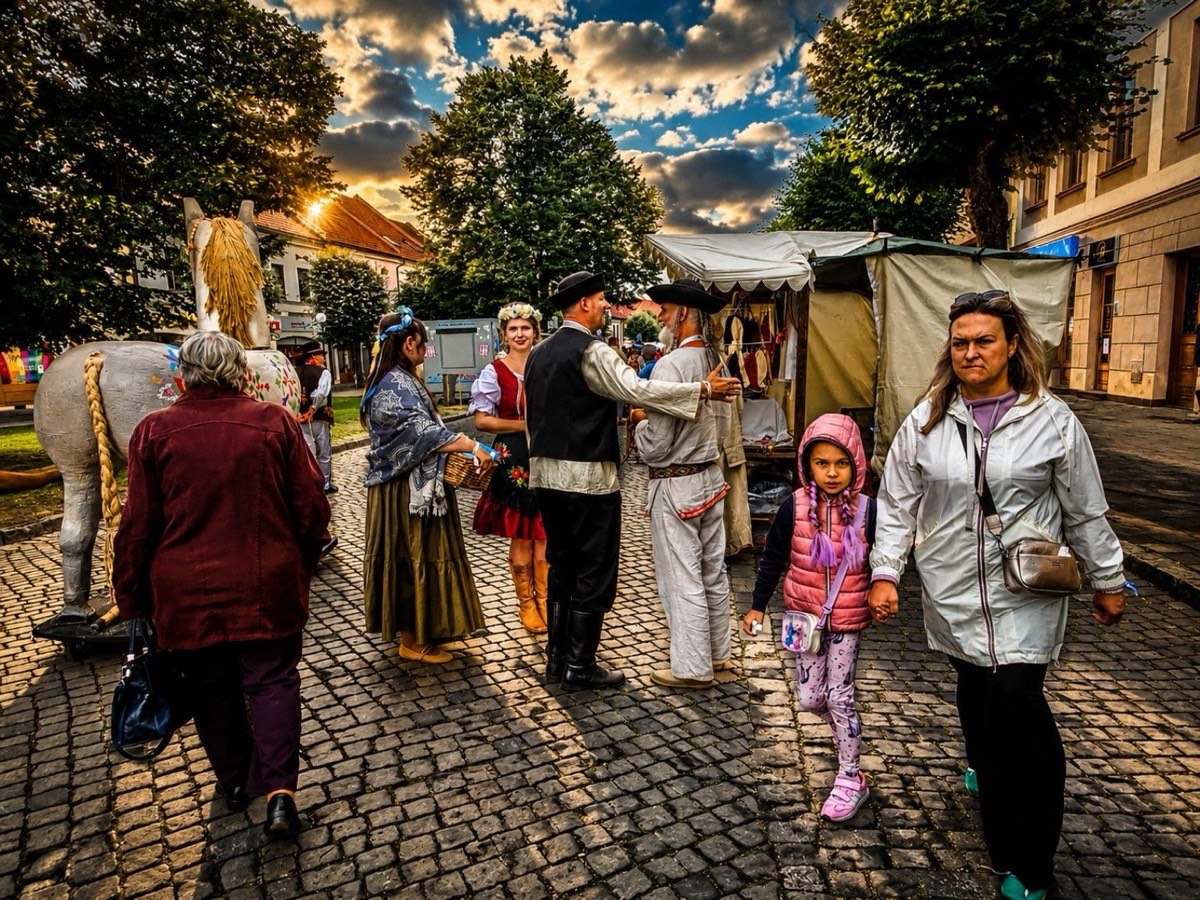 Účinkujúci v krojoch pri remeselnom stánku počas západu slnka na EĽRO 2026